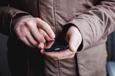 Adam akıllı bir telefon kullanıyor. Modern cep telefonu elinde..