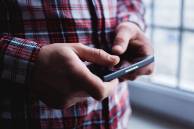 Adam akıllı bir telefon kullanıyor. Modern cep telefonu elinde..