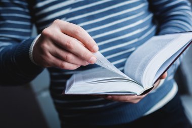 Adam okuyor. Kitap onun elinde..
