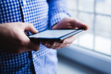 Adam tablet bilgisayar kullanıyor. Elinde modern bir alet..