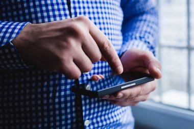 Adam akıllı bir telefon kullanıyor. Modern cep telefonu elinde..