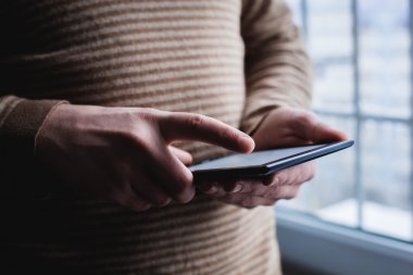 Adam tablet bilgisayar kullanıyor. Elinde modern bir alet..