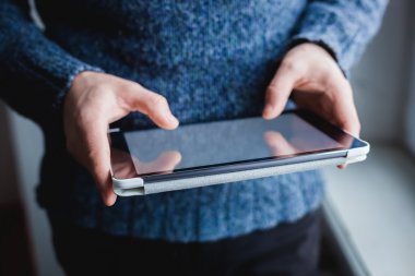 Adam tablet bilgisayar kullanıyor. Elinde modern bir alet..