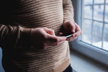 Adam akıllı bir telefon kullanıyor. Modern cep telefonu elinde..
