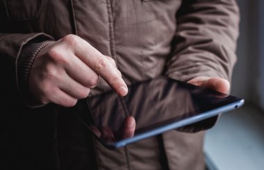 Adam tablet bilgisayar kullanıyor. Elinde modern bir alet..