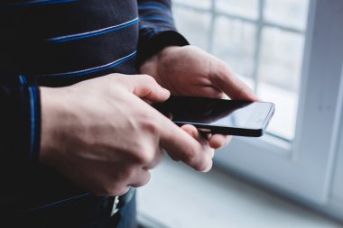 Adam akıllı bir telefon kullanıyor. Modern cep telefonu elinde..