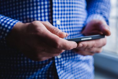 Adam akıllı bir telefon kullanıyor. Modern cep telefonu elinde..