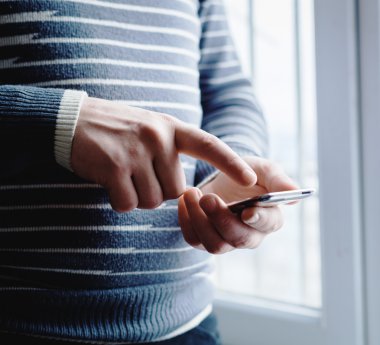 Adam akıllı bir telefon kullanıyor. Modern cep telefonu elinde..
