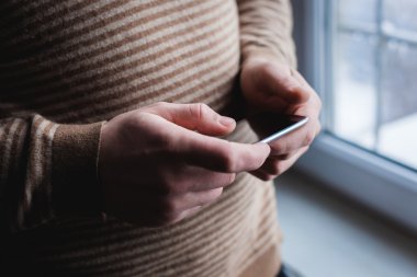 Adam akıllı bir telefon kullanıyor. Modern cep telefonu elinde..