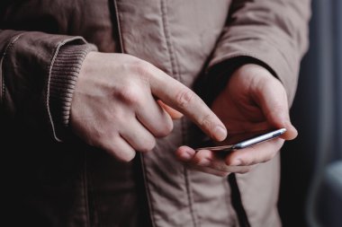 Adam akıllı bir telefon kullanıyor. Modern cep telefonu elinde..