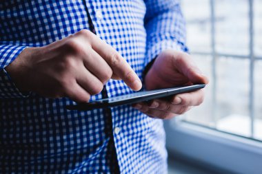 Adam tablet bilgisayar kullanıyor. Elinde modern bir alet..