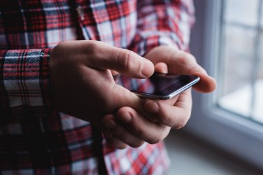 Adam akıllı bir telefon kullanıyor. Modern cep telefonu elinde..