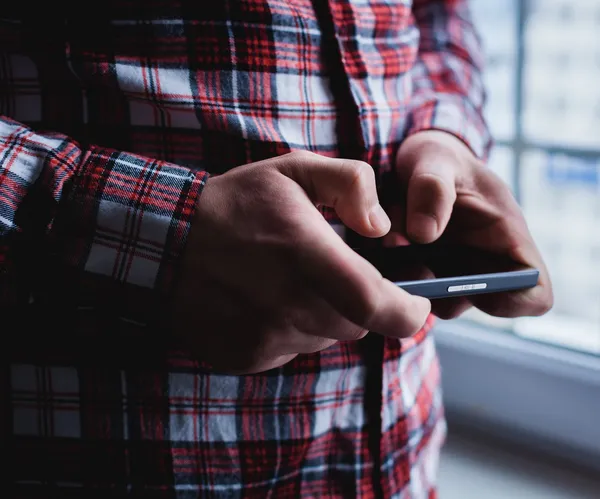 O homem está usando um smartphone. Telemóvel moderno na mão . — Fotografia de Stock