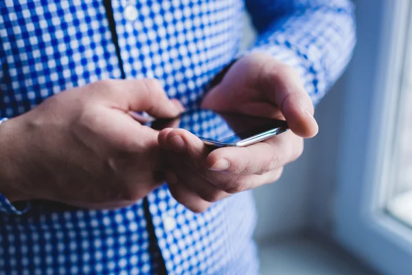 The man is using a smartphone. Modern mobile phone in hand. — Stock Photo, Image