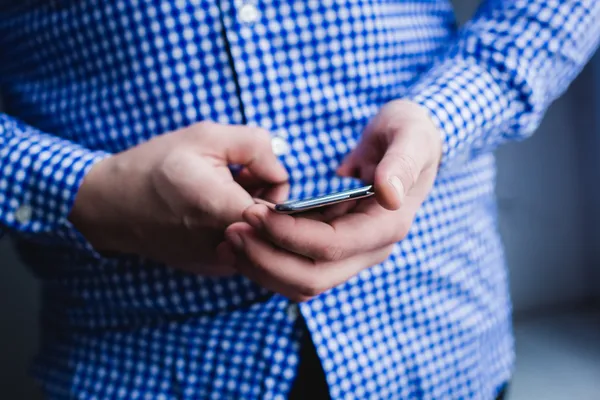 The man is using a smartphone. Modern mobile phone in hand. — Stock Photo, Image