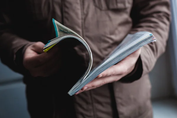 Un hombre mira una revista. Presione las manos . — Foto de Stock