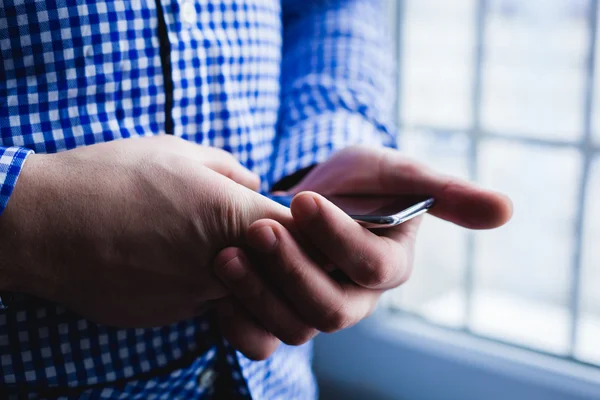 El hombre está usando un teléfono inteligente. Teléfono móvil moderno en la mano . — Foto de Stock