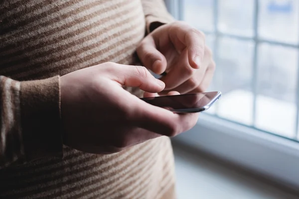 O homem está usando um smartphone. Telemóvel moderno na mão . — Fotografia de Stock