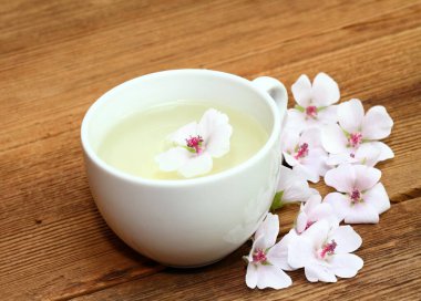 Marshmallow 'dan çay. Althaea officinalis, öksürüğe karşı iyidir. Kahverengi ahşap tahta Marsh Mallow çiçekleriyle süslenir.