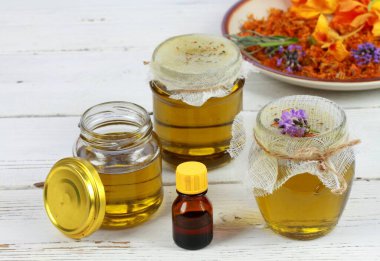 Kavanozda filtreledikten sonra şifalı bitkilerden elde edilen doğal yağ. Ev yapımı tıbbi yağ beyaz masadaki cilt için iyidir..