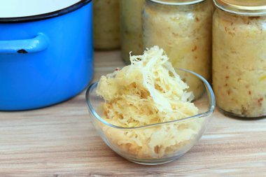 Lahana turşusu kasede ve kavanozlarda yemeye hazır. En iyi probiyotik, ahşap masa ile dolu ev yapımı bir Alman..