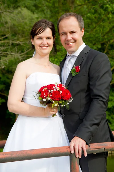Frisch verheiratetes Paar mit roten Rosen — Stockfoto