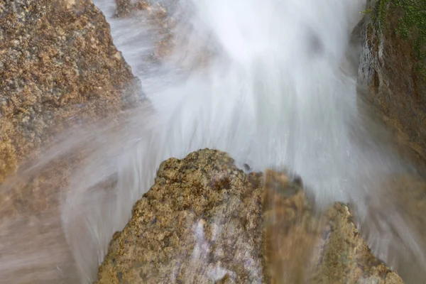 Чистая, речная вода брызгает вниз над камнями — стоковое фото