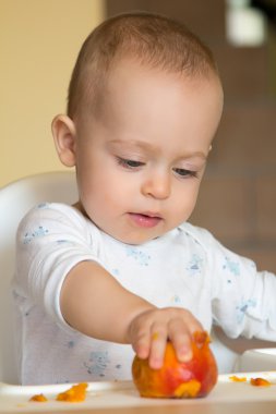 meraklı bir bebek şeftali ele alıyor.