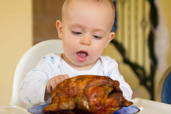 Малыш ест большую курицу на гриле — стоковое фото