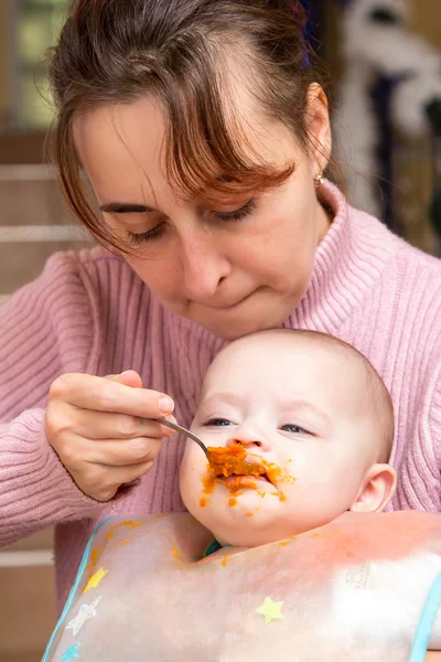 Mamá alimenta a la niña con cuchara — Foto de Stock