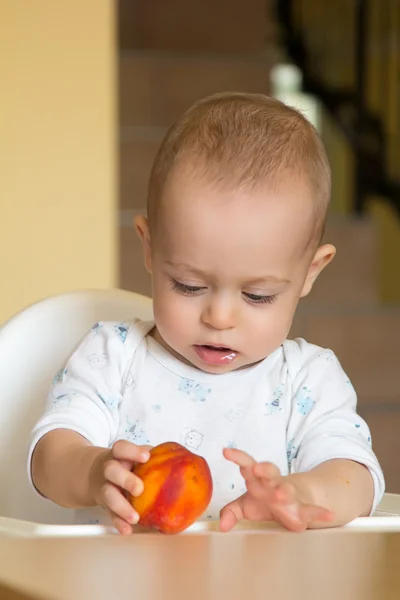 Curioso bebé niño examina un melocotón — Foto de Stock