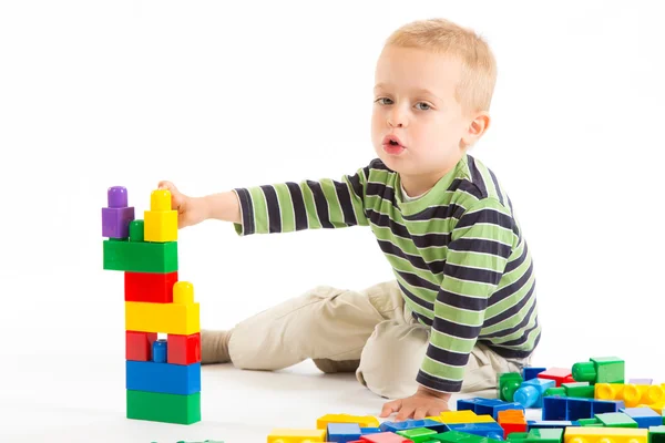 Piccolo ragazzo carino che gioca con i mattoni. Isolato su bianco . — Foto Stock