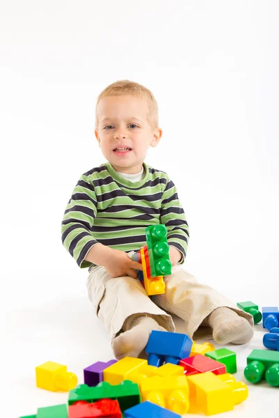 Piccolo ragazzo carino che gioca con i mattoni. Isolato su bianco . — Foto Stock