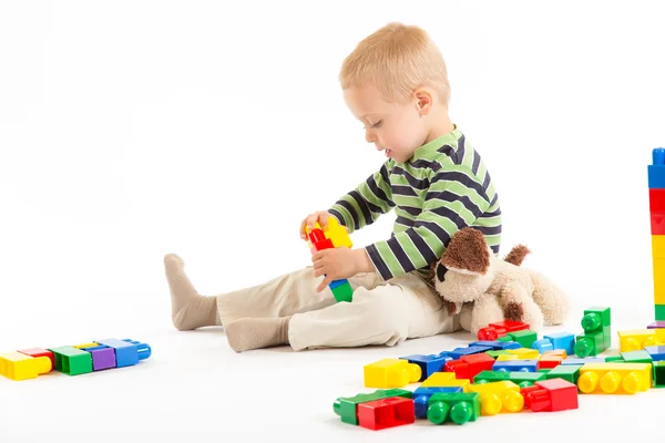 Liten söt pojke leker med byggstenar. isolerad på vit. Stockfoto