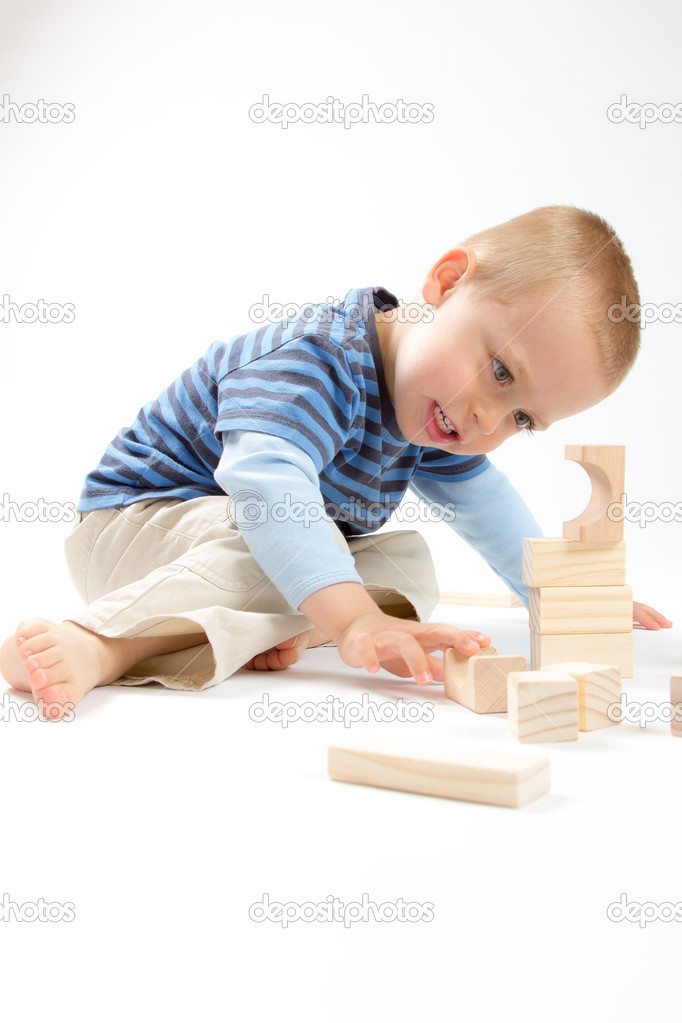 Little cute boy playing with building blocks. Isolated on white.