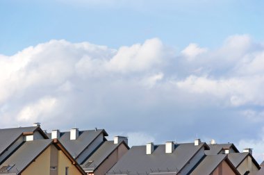 Row house roofs, condo rooftop panorama and bright summer cloudscape clipart