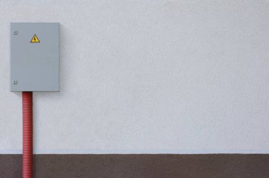 Elektrik dağıtım kabloları açık hava telefon paneli gri dağıtım kutusu dolabı sarı yüksek gerilim üçgeni kırmızı kıvrımlı kıvrımlı kablo kaplama HDPE boru bej rengi duvar sıva dokusu arka plan boş yatay fotokopi alanı