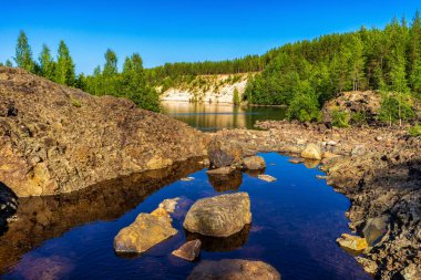 Yazın güneşli bir günde taştan kayalar ve kuzey ormanları arasında nehir olan güzel bir manzara. Paleovolcano Girvas, eşsiz jeolojik nesne, en eski volkan krateri. Rusya, Karelia 'daki Girvas Parkı.