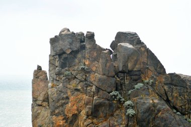 Photo of some weathered eroded cracked rocks on the coastline