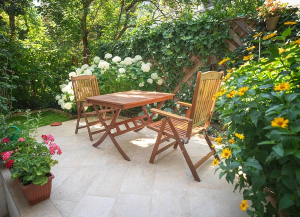 花园里有漂亮花朵的桌子和椅子 — 图库照片