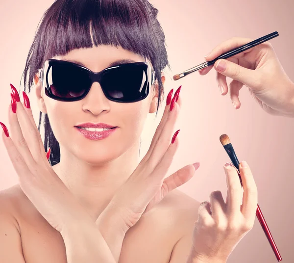 Mãos aplicando maquiagem em um rosto de mulher — Fotografia de Stock