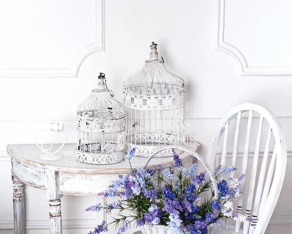 Vintage chair and table with flower in front and cages — Stock Photo, Image