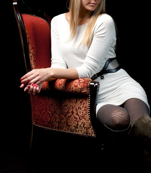 Frau sitzt auf Stuhl vor isoliertem schwarzen Hintergrund — Stockfoto