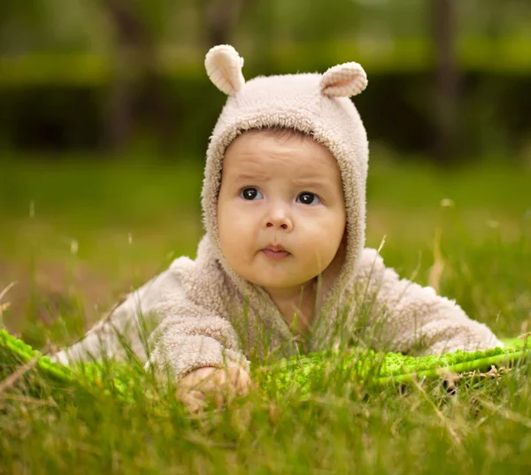 Yeşil çimenlerin üzerinde oturan küçük kız — Stok fotoğraf
