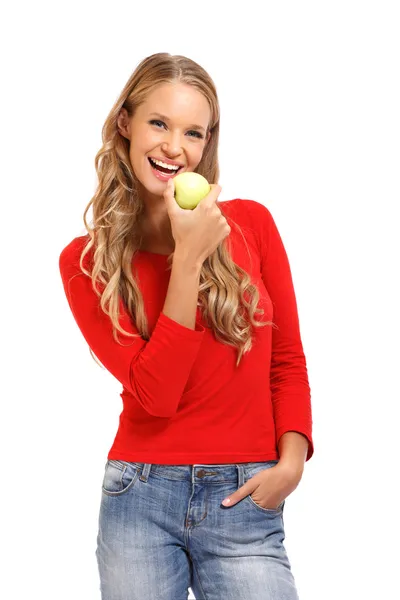 年轻的金发女人吃苹果的孤立的肖像 图库照片