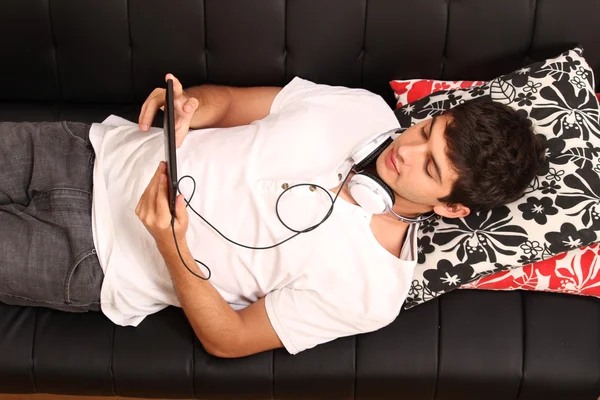 Young man with a Tablet PC and Headphones on the Sofa — Stock Photo, Image