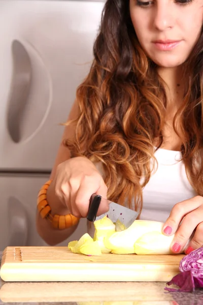 Jeune femme coupant des légumes — Photo