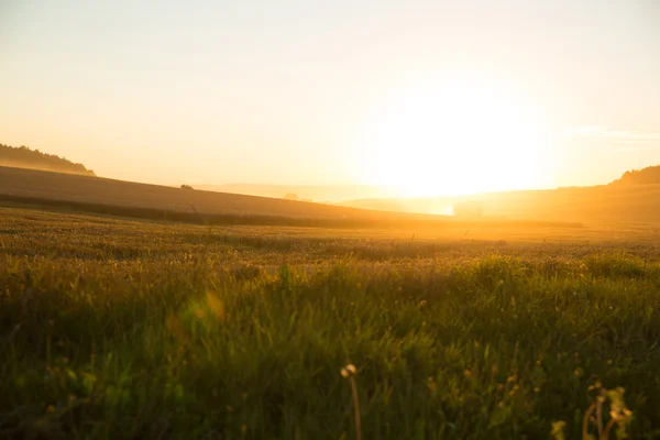 Pôr do sol sobre um campo colhido — Fotografia de Stock