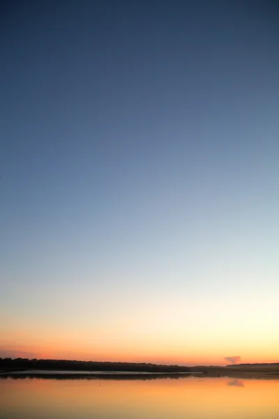 Auringonlasku järven yllä — kuvapankkivalokuva