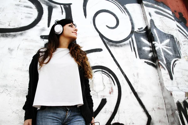 Fille écouter de la musique tout en s'appuyant sur un mur — Photo